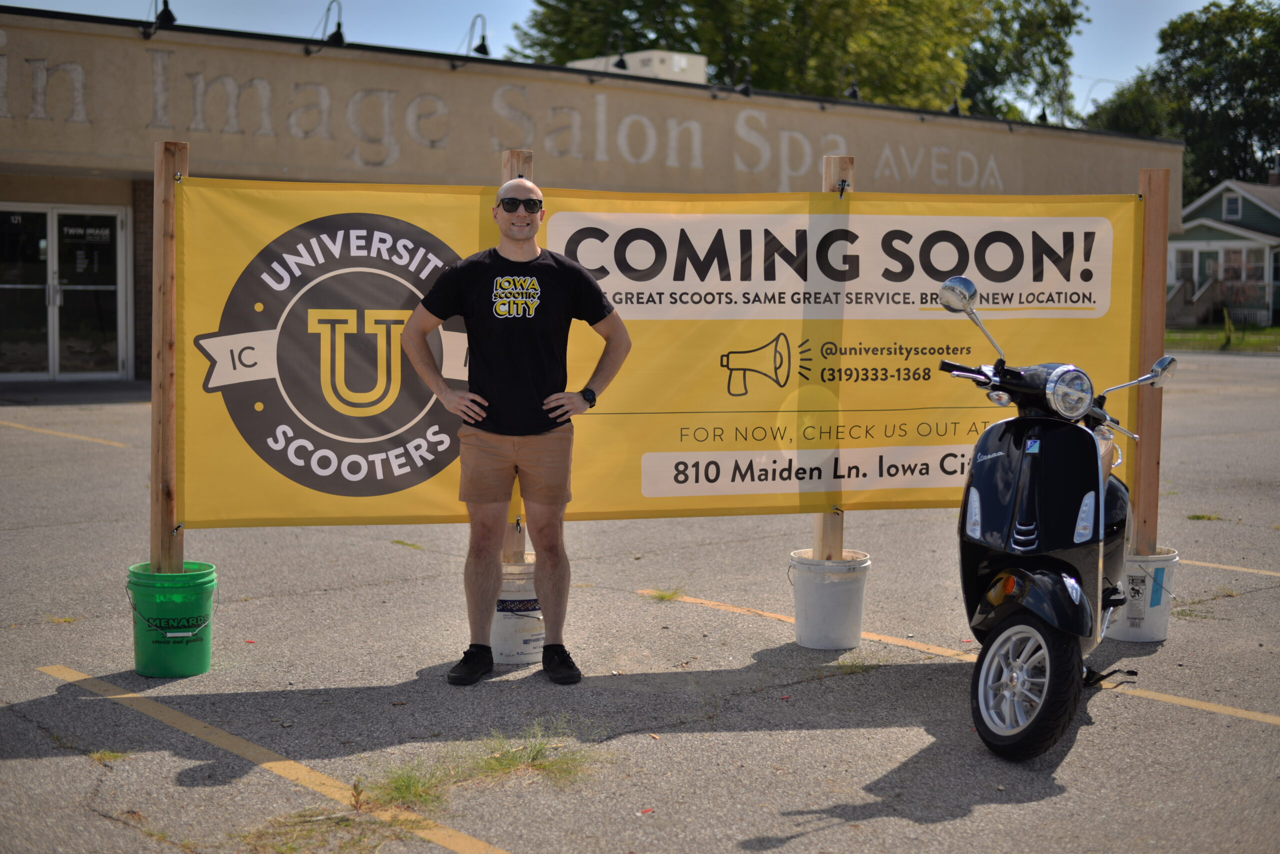 University Scooters owner Tyler Presinger stands next to a sign that reads 